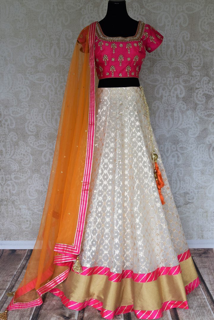Leave them spellbound as you show up in this jaw-dropping white chanderi silk lehenga accompanied with a stunning hot pink zardosi embroidered blouse. Complete the look with the orange sequinned net dupatta with pink border. Shop Indian dress, lehenga choli, ikkat sari online or visit Pure Elegance store, USA.-full view