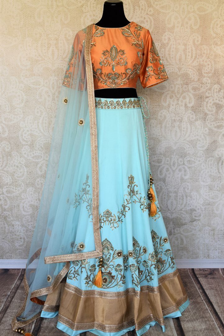 Doll up chic in this statement-worthy blue embroidery designer lehenga paired with contrasting orange embroidered designer blouse and buta work powder blue sheer net dupatta to add grace. Shop handcrafted designer dresses, indo-western dresses, lehengas online or visit Pure Elegance store in USA. -full view