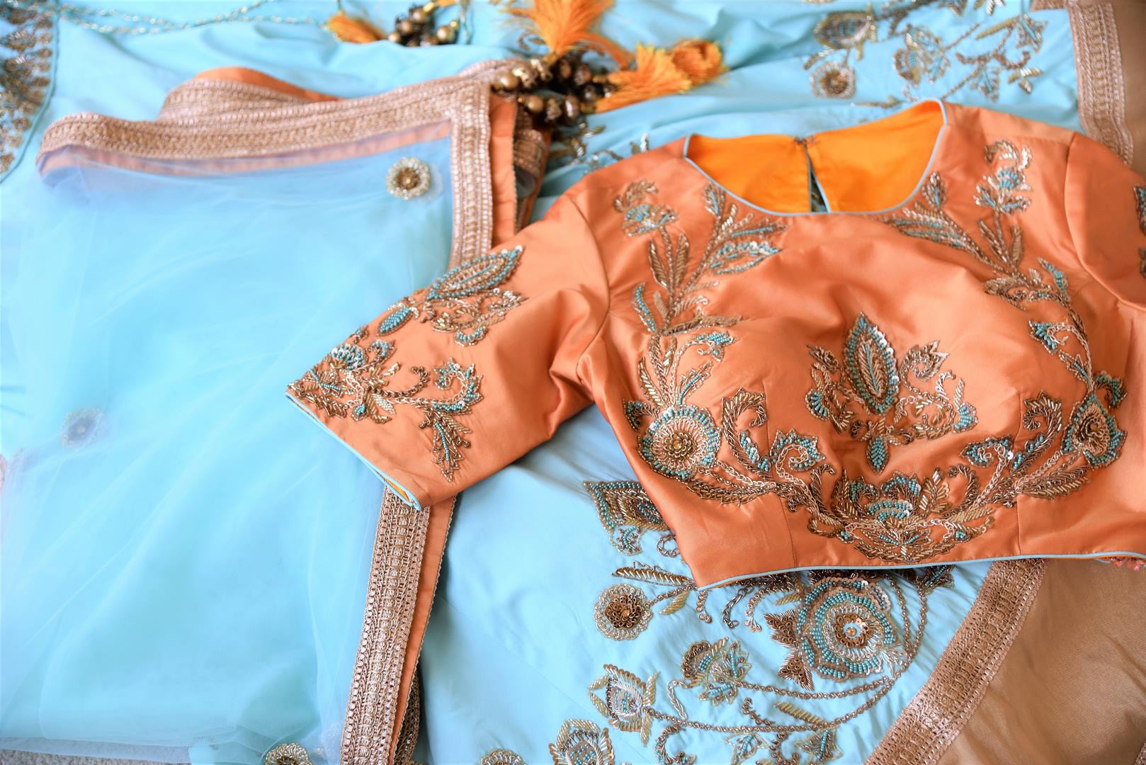 Doll up chic in this statement-worthy blue embroidery designer lehenga paired with contrasting orange embroidered designer blouse and buta work powder blue sheer net dupatta to add grace. Shop handcrafted designer dresses, indo-western dresses, lehengas online or visit Pure Elegance store in USA. -details