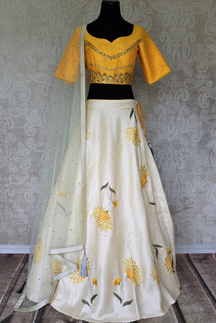Be an epitome of grace in this designer white raw silk embroidered lehenga. Style this gorgeous lehenga with a mellow yellow embroidered blouse with a sweetheart neckline. Drape a pristine white sequin work laden dupatta. Shop Indian dresses, lehenga cholis, anarkali suits online or visit Pure Elegance store, USA. -full view