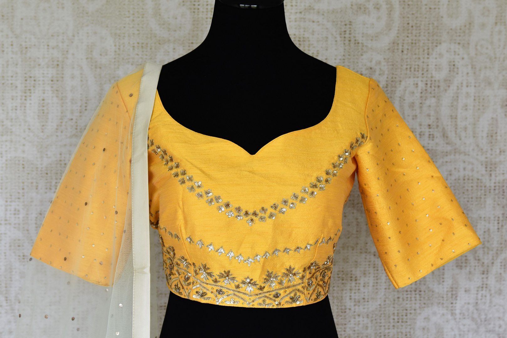 Be an epitome of grace in this designer white raw silk embroidered lehenga. Style this gorgeous lehenga with a mellow yellow embroidered blouse with a sweetheart neckline. Drape a pristine white sequin work laden dupatta. Shop Indian dresses, lehenga cholis, anarkali suits online or visit Pure Elegance store, USA. -blouse front