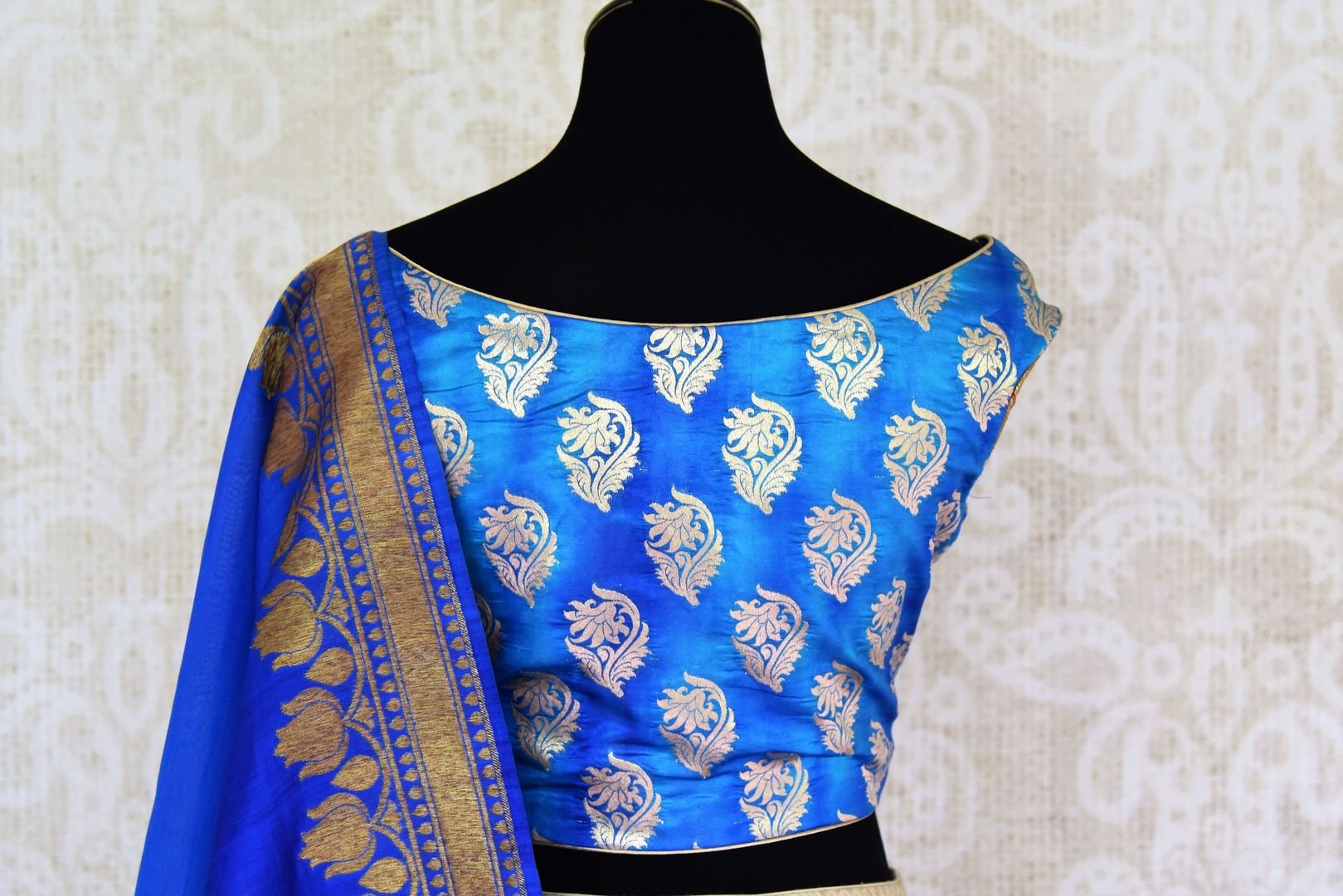 Buy gold Banarasi silk lehenga with blue sleeveless choli online in USA and dupatta. Find a range of stunning designer lehengas in USA at Pure Elegance Indian clothing store. Elevate your traditional style with a range of designer sarees, Indian clothing, and much more also available at our online store.-blouse back