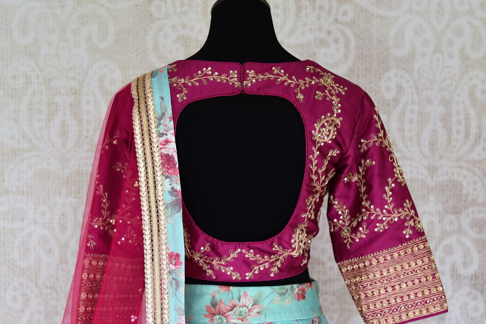 Shop blue floral silk lehenga with magenta embroidered blouse online in USA and dupatta. Find a range of stunning designer lehengas in USA at Pure Elegance Indian clothing store. Elevate your traditional style with a range of designer saris, Indian clothing, and much more also available at our online store.-blouse back