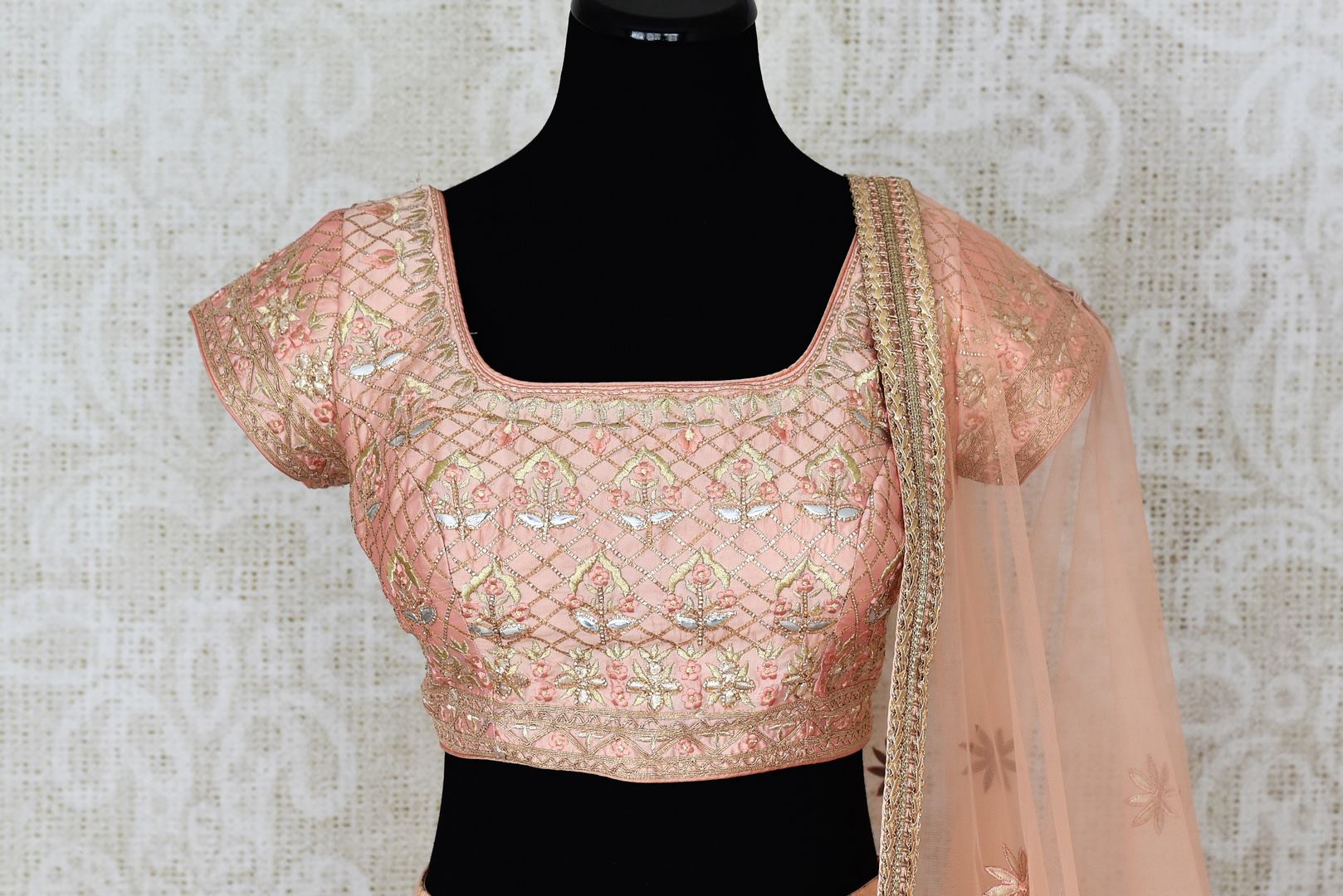 Buy peach net and silk embroidered lehenga online in USA with dupatta. Pick your favorite Indian clothing from a colorful collection available at Pure Elegance Indian fashion store in USA. We have an alluring range of wedding lehengas, designer Anarkali suits, gowns for Indian women in USA.-blouse front