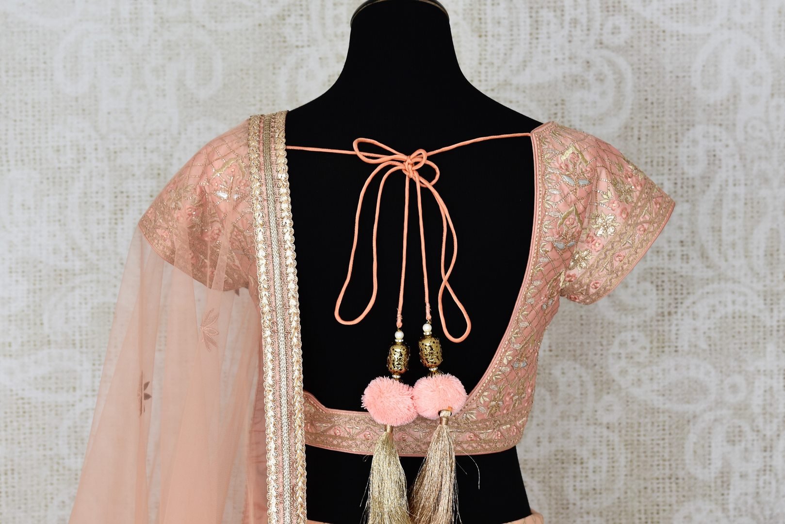 Buy peach net and silk embroidered lehenga online in USA with dupatta. Pick your favorite Indian clothing from a colorful collection available at Pure Elegance Indian fashion store in USA. We have an alluring range of wedding lehengas, designer Anarkali suits, gowns for Indian women in USA.-blouse back