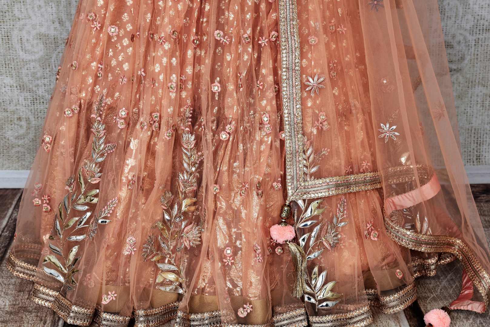 Buy peach net and silk embroidered lehenga online in USA with dupatta. Pick your favorite Indian clothing from a colorful collection available at Pure Elegance Indian fashion store in USA. We have an alluring range of wedding lehengas, designer Anarkali suits, gowns for Indian women in USA.-skirt