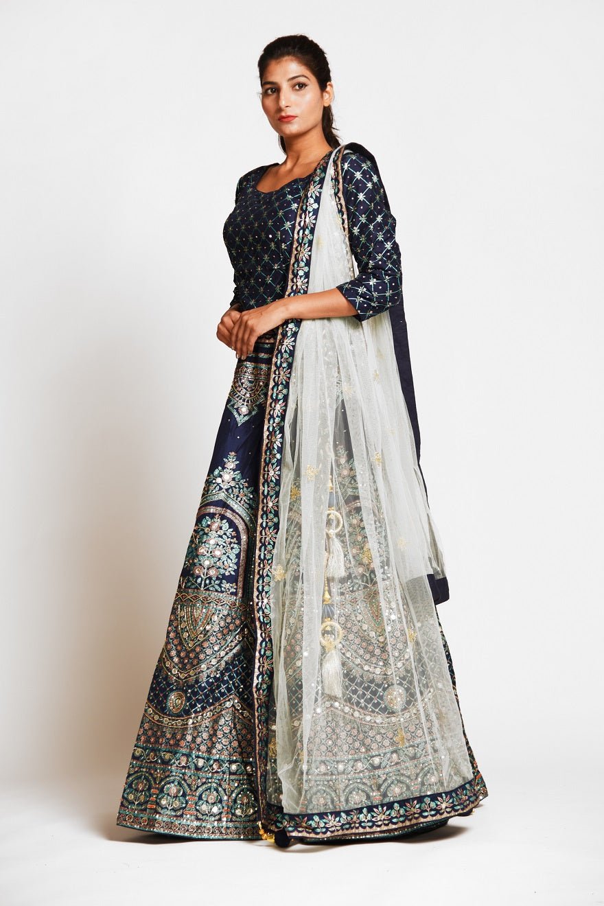 Buy navy blue embroidered designer silk lehenga online in USA with white net dupatta. Elevate your traditional Indian style with exquisite designer lehengas, Anarkali suits, traditional salwar suits from Pure Elegance Indian clothing store in USA.-left side
