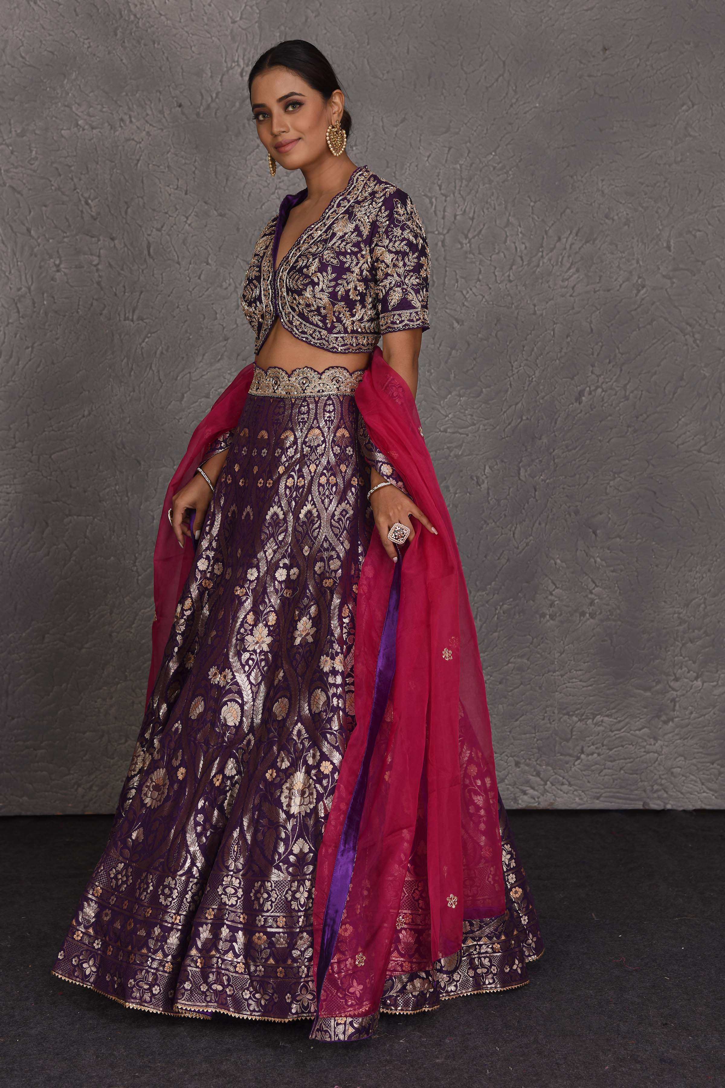 Shop purple hand embroidered Banarasi lehenga online in USA with pink dupatta. Flaunt your Indian style on festive occasions in stunning designer lehengas, Anarkali suit, sharara suits, designer gowns, designer sarees, embroidered sarees from Pure Elegance India fashion store in USA. -side