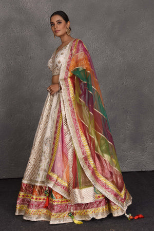 Buy cream embroidered lehenga online in USA with multicolor border. Flaunt your Indian style on festive occasions in stunning designer lehengas, Anarkali suit, sharara suits, designer gowns, designer sarees, embroidered sarees from Pure Elegance India fashion store in USA. -dupatta
