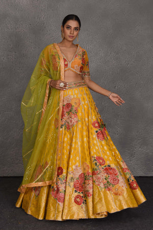 Shop yellow Banarasi floral lehenga online in USA with green net dupatta. Flaunt your Indian style on festive occasions in stunning designer lehengas, Anarkali suit, sharara suits, designer gowns, designer sarees, embroidered sarees from Pure Elegance India fashion store in USA. -front