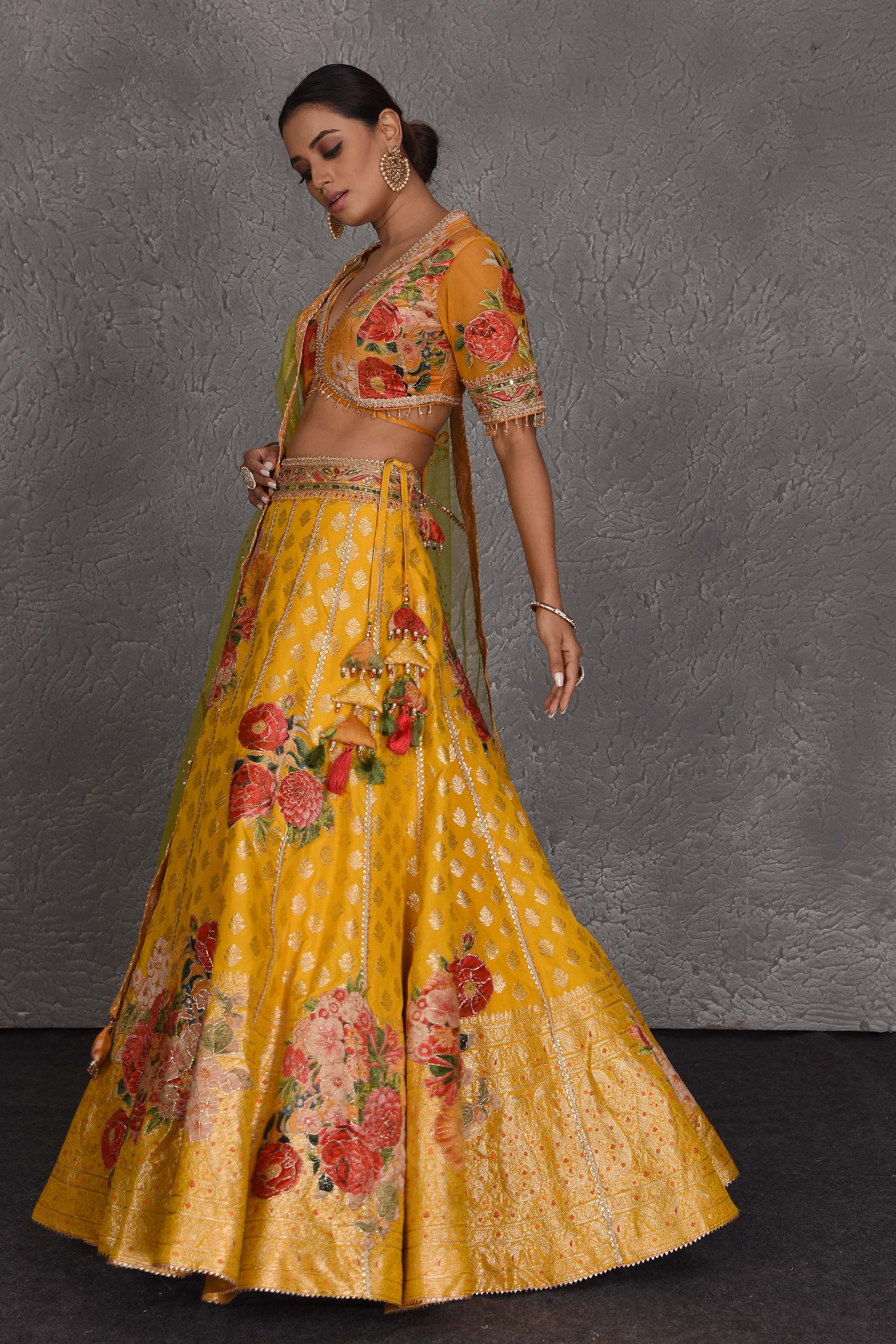 Shop yellow Banarasi floral lehenga online in USA with green net dupatta. Flaunt your Indian style on festive occasions in stunning designer lehengas, Anarkali suit, sharara suits, designer gowns, designer sarees, embroidered sarees from Pure Elegance India fashion store in USA. -side