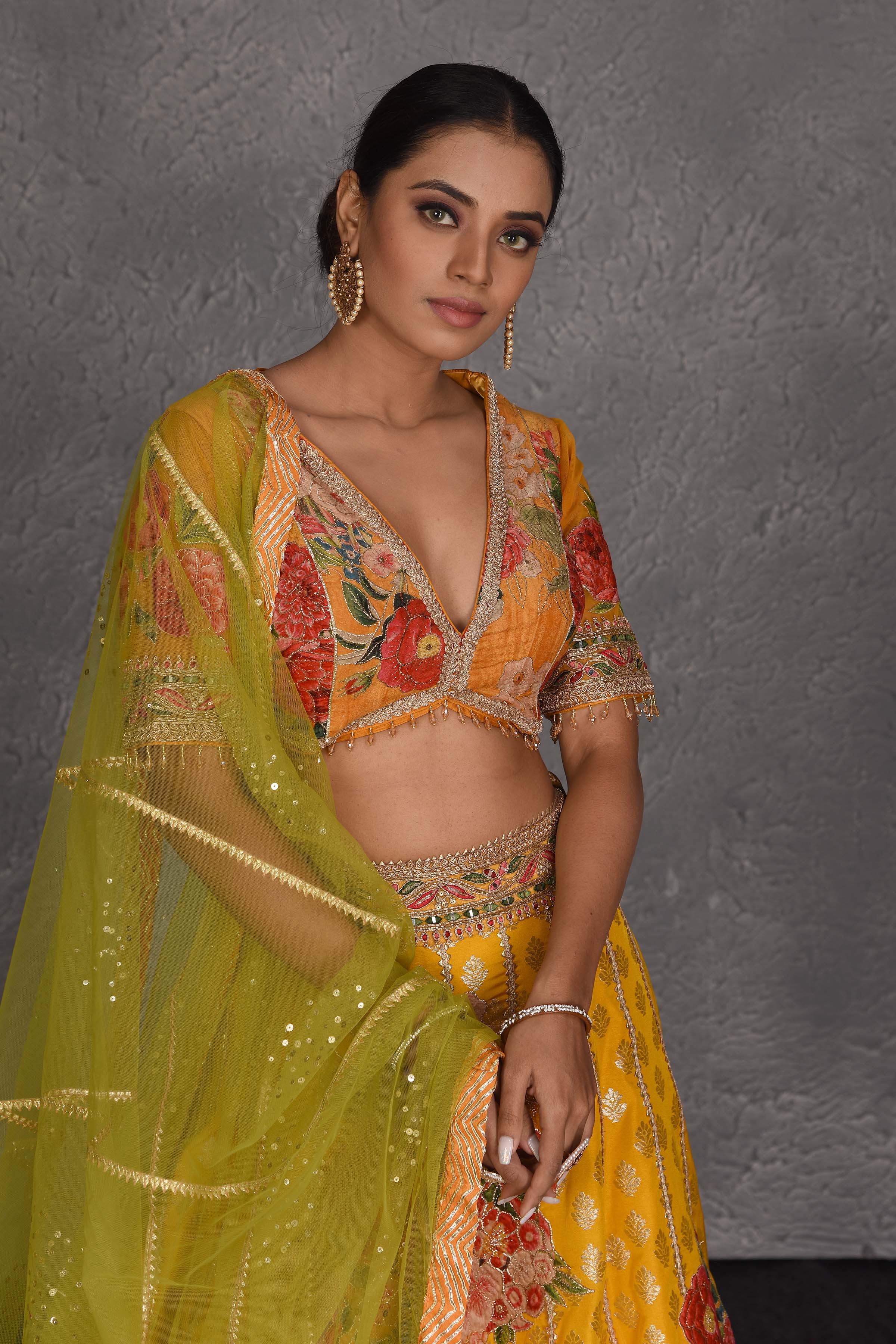 Shop yellow Banarasi floral lehenga online in USA with green net dupatta. Flaunt your Indian style on festive occasions in stunning designer lehengas, Anarkali suit, sharara suits, designer gowns, designer sarees, embroidered sarees from Pure Elegance India fashion store in USA. -closeup