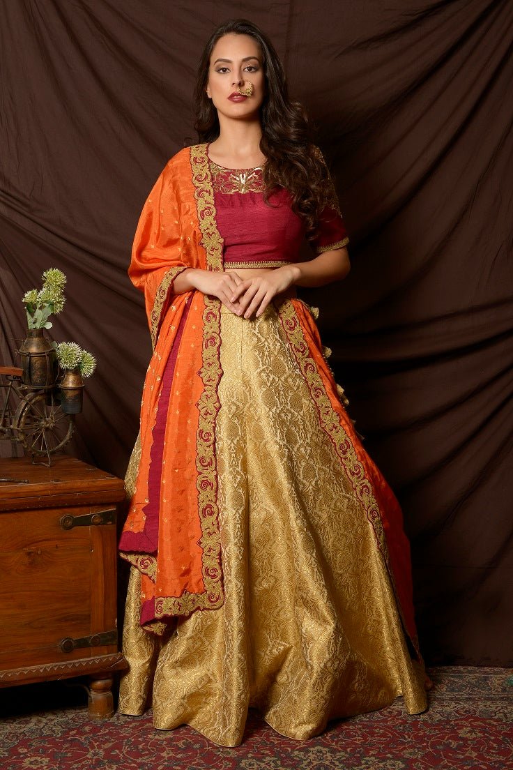 Buy gorgeous maroon and green embroidered brocade lehenga online in USA with orange dupatta. Shine at weddings and special occasions with beautiful Indian designer dresses, gowns, lehengas from Pure Elegance Indian clothing store in USA.-front
