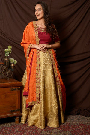 Buy gorgeous maroon and green embroidered brocade lehenga online in USA with orange dupatta. Shine at weddings and special occasions with beautiful Indian designer dresses, gowns, lehengas from Pure Elegance Indian clothing store in USA.-lehenga