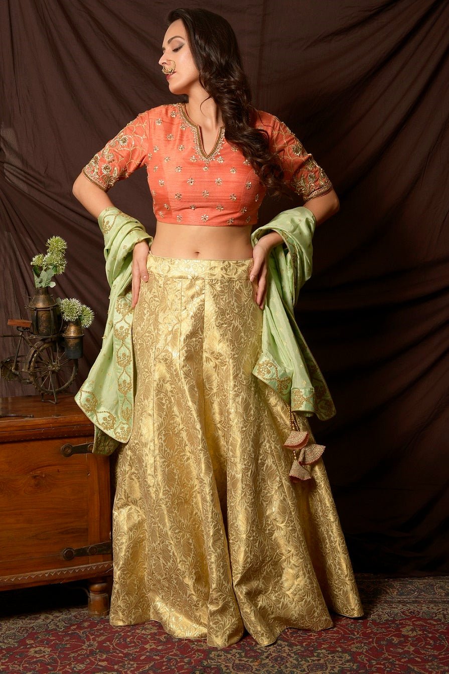 Shop gorgeous peach and gold embroidered brocade lehenga online in USA with pista green dupatta. Shine at weddings and special occasions with beautiful Indian designer dresses, gowns, lehengas from Pure Elegance Indian clothing store in USA.-front