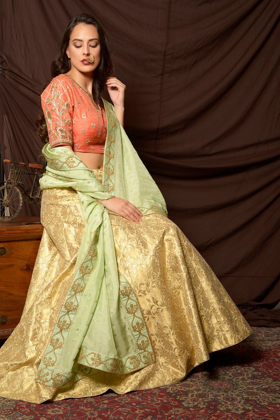 Shop gorgeous peach and gold embroidered brocade lehenga online in USA with pista green dupatta. Shine at weddings and special occasions with beautiful Indian designer dresses, gowns, lehengas from Pure Elegance Indian clothing store in USA.-closeup