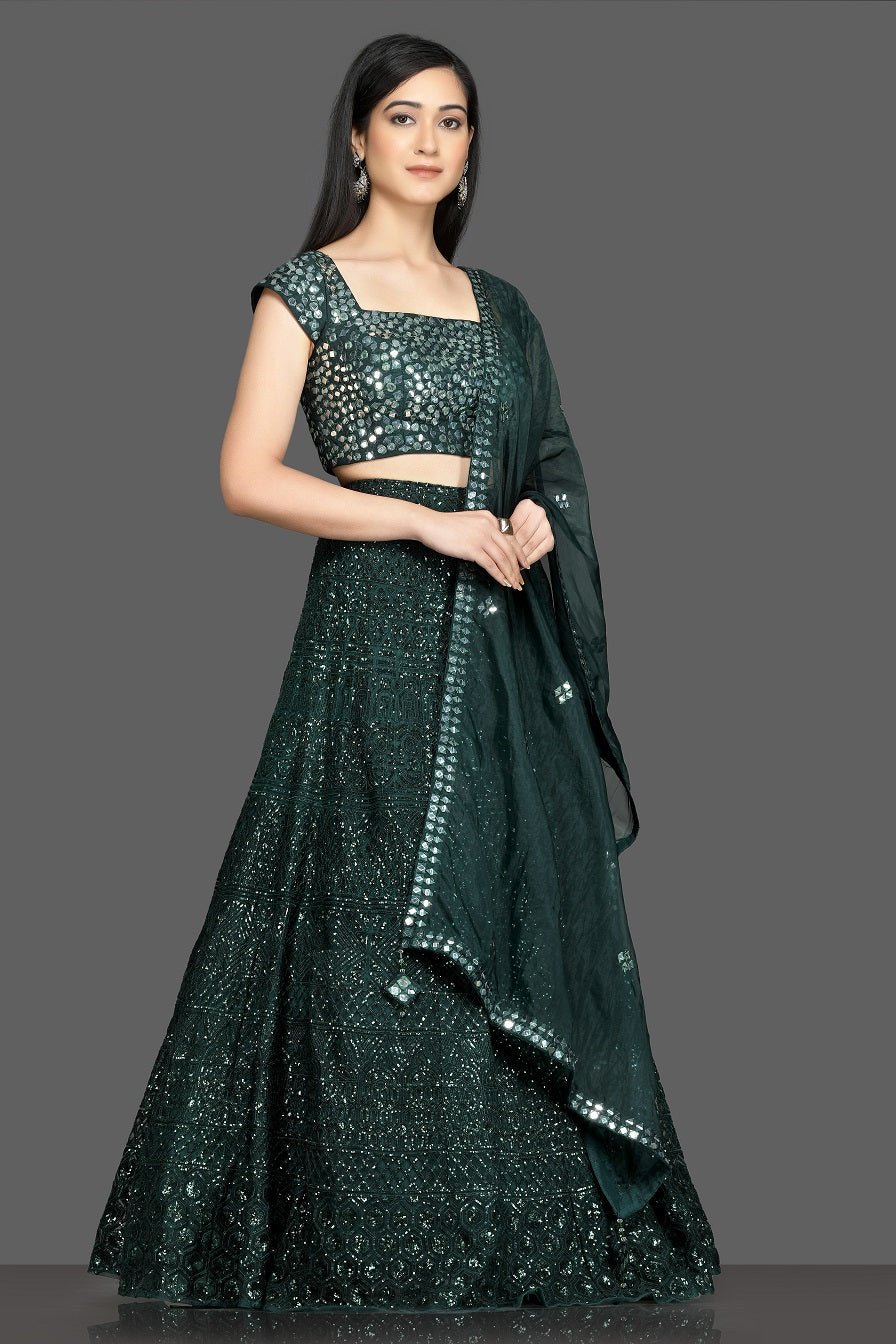 Shop stunning dark green mirror work lehenga online in USA with net dupatta. Dazzle on weddings and special occasions with exquisite Indian designer dresses, sharara suits, Anarkali suits, bridal lehegas from Pure Elegance Indian fashion store in USA.-side