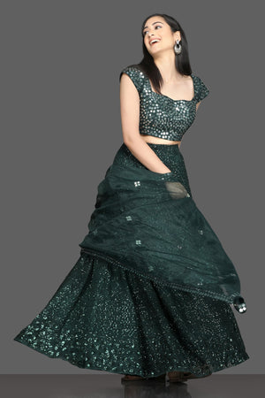 Shop stunning dark green mirror work lehenga online in USA with net dupatta. Dazzle on weddings and special occasions with exquisite Indian designer dresses, sharara suits, Anarkali suits, bridal lehegas from Pure Elegance Indian fashion store in USA.-front