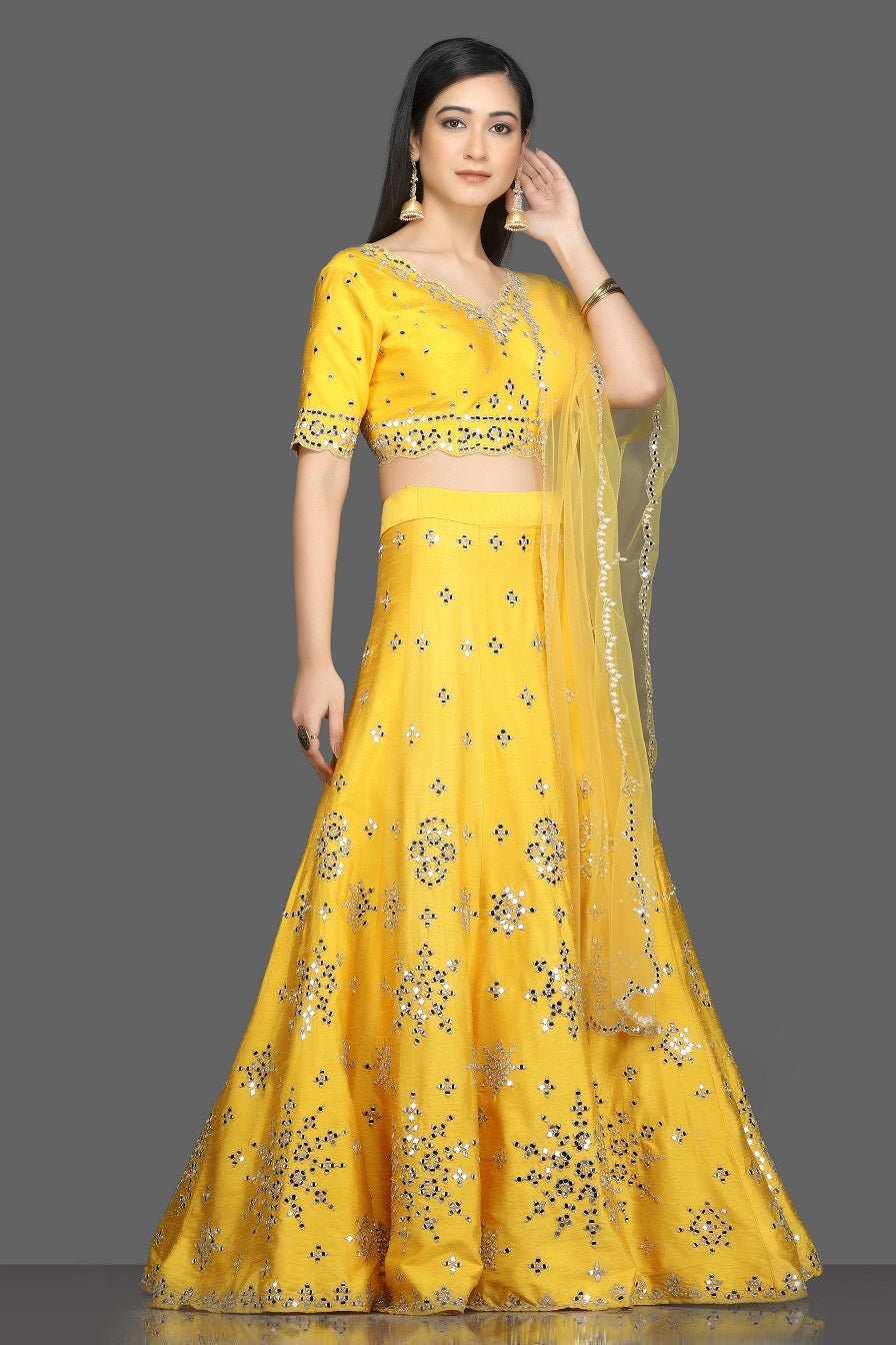 Shop gorgeous bright yellow mirror work lehenga online in USA with net dupatta. Dazzle on weddings and special occasions with exquisite Indian designer dresses, sharara suits, Anarkali suits, bridal lehegas from Pure Elegance Indian fashion store in USA.-side