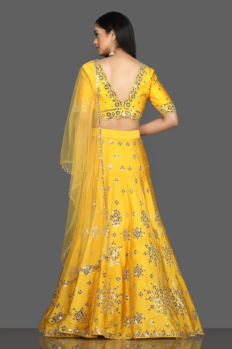 Shop gorgeous bright yellow mirror work lehenga online in USA with net dupatta. Dazzle on weddings and special occasions with exquisite Indian designer dresses, sharara suits, Anarkali suits, bridal lehegas from Pure Elegance Indian fashion store in USA.-back