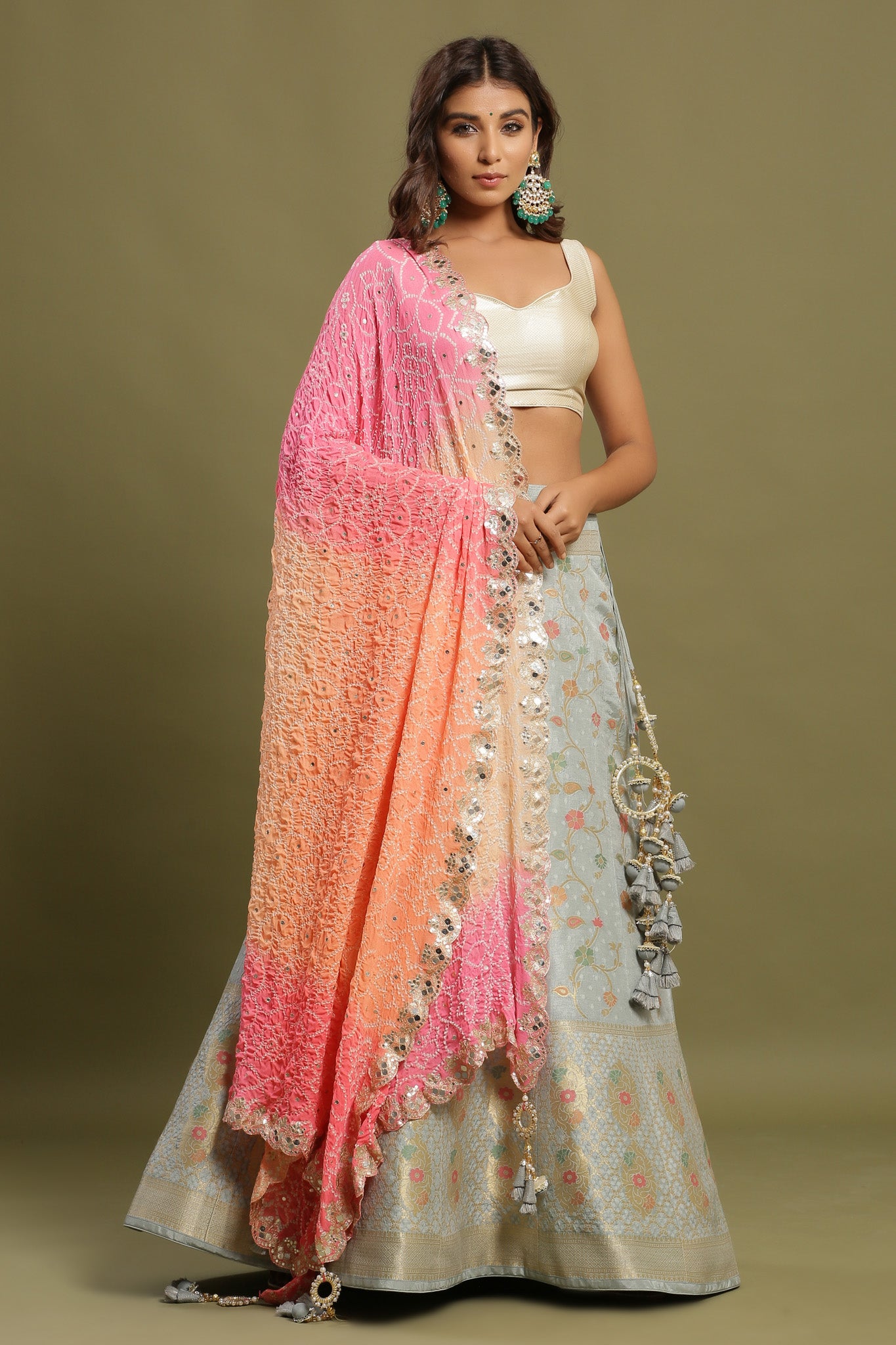 Shop a Beautiful grey silk lehenga with a multicolor dupatta. The lehenga is perfect for weddings and sangeet parties. It is crafted in silk with intrinsic floral self-design work, tassels, and a beautiful off-white blouse. Shop online from Pure Elegance.