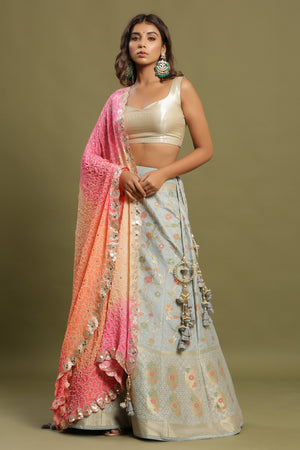 Shop a Beautiful grey silk lehenga with a multicolor dupatta. The lehenga is perfect for weddings and sangeet parties. It is crafted in silk with intrinsic floral self-design work, tassels, and a beautiful off-white blouse. Shop online from Pure Elegance.