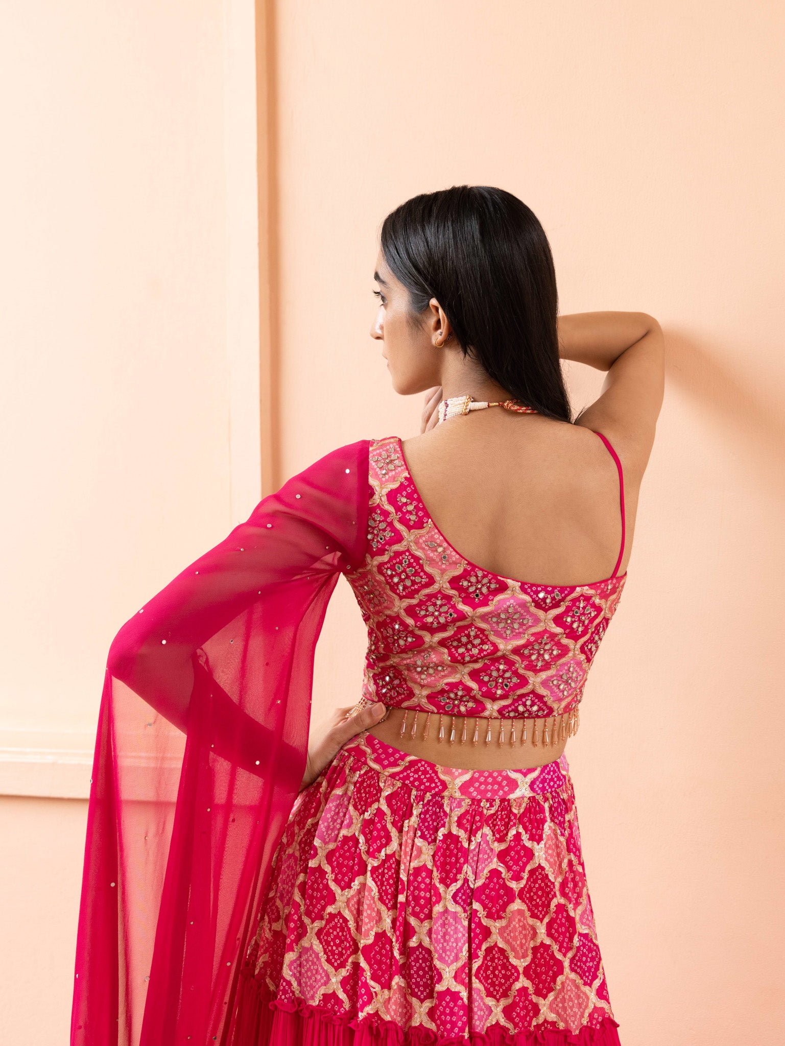 Shop a stylish contemporary fuchsia pink georgette sleeveless lehenga with a one-sided attached dupatta. Perfect for wedding occasions online in the USA . Dazzle on weddings and special occasions with exquisite Indian designer dresses, sharara suits, Anarkali suits, and wedding lehengas from Pure Elegance Indian fashion store in USA.- Back View