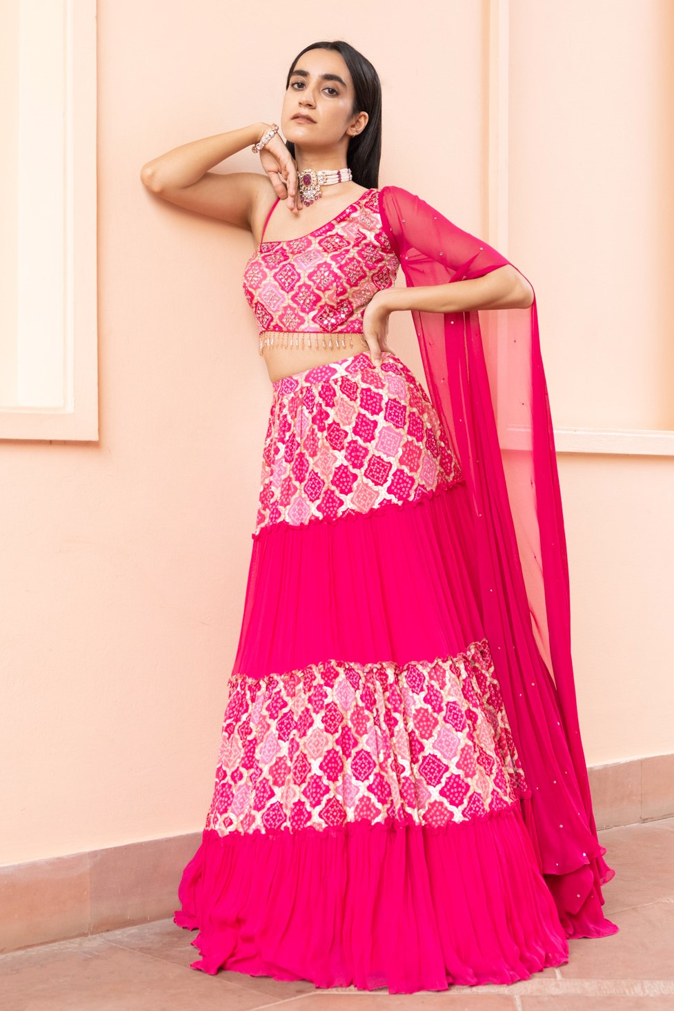 Shop a stylish contemporary fuchsia pink georgette sleeveless lehenga with a one-sided attached dupatta. Perfect for wedding occasions online in the USA . Dazzle on weddings and special occasions with exquisite Indian designer dresses, sharara suits, Anarkali suits, and wedding lehengas from Pure Elegance Indian fashion store in USA.- Front Image
