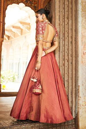 Gorgeous rust color embroidered tissue lehenga with dupatta is a perfect choice for a sangeet and engagement parties. The lehenga is adorned with beautiful embroidery and a contrasting dupatta. Shop designer Indian lehengas in USA from Pure Elegance.- Back View