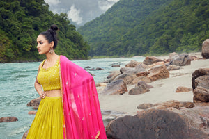 Shop exquisite yellow lehenga with pink dupatta. The lehenga is perfect for haldi and sangeet parties. It is crafted in silk with beautiful embroidery, cut dana, and a sleeveless blouse. Shop online from Pure Elegance.