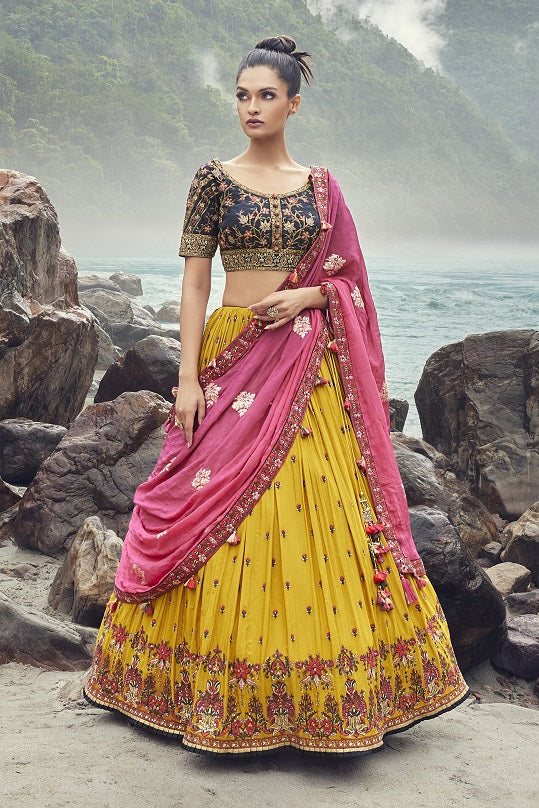 Shop an exquisite yellow lehenga with a pink georgette dupatta. The lehenga is perfect for haldi and sangeet parties. It is crafted in georgette with beautiful embroidery, cut dana, and an embroidered blouse. Shop online from Pure Elegance.