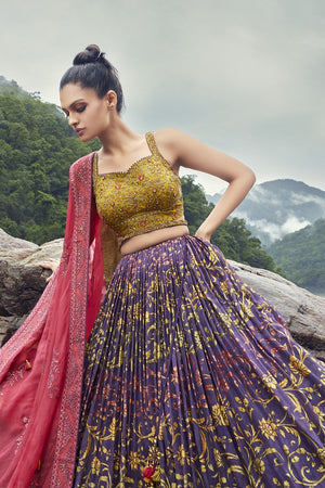 Shop an exquisite purple lehenga with a pink dupatta. The lehenga is perfect for cocktail and sangeet parties. It is crafted in georgette with beautiful floral self-embroidery and a sleeveless blouse. Shop online from Pure Elegance.