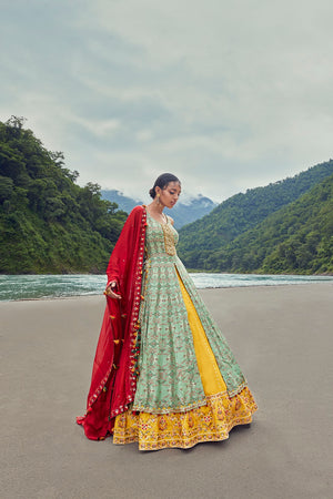 Shop this beautiful yellow lehenga with an embellished blue long kurti. The lehenga is perfect for sangeet ceremonies. It is crafted with intricate embroidery work and a red dupatta. Shop online from Pure Elegance.