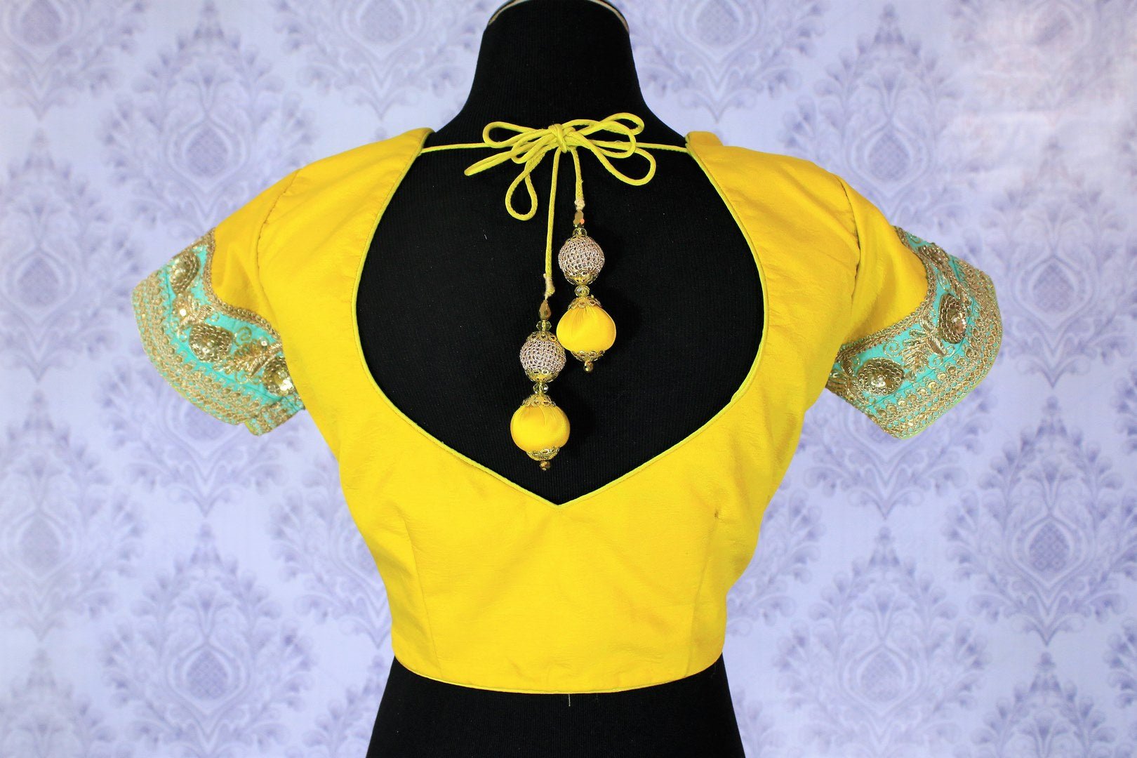 Amp up your dressing game with our gorgeously handcrafted yellow embroidered designer sari blouse with turquoise and gold zari detailing. Shop the beautiful saree blouse for special occasions and events online or visit Pure Elegance store in USA. -back