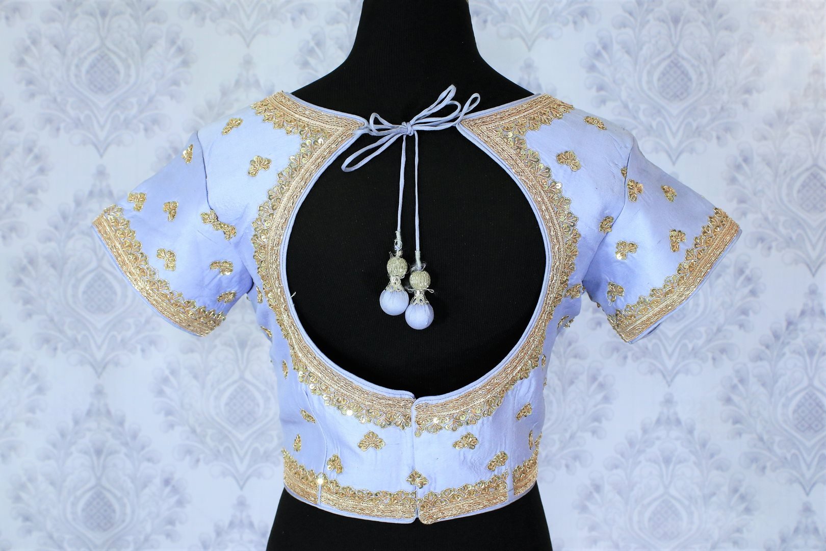 This celebrity-inspired powder blue coloured pastel blouse with stunning gold embroidery is quite a tempting bait. The wide keyhole with tassels hanging at the back further create drama and add grace to the feminine look. Shop beautifully handcrafted blouses online or visit Pure Elegance store in USA.-back