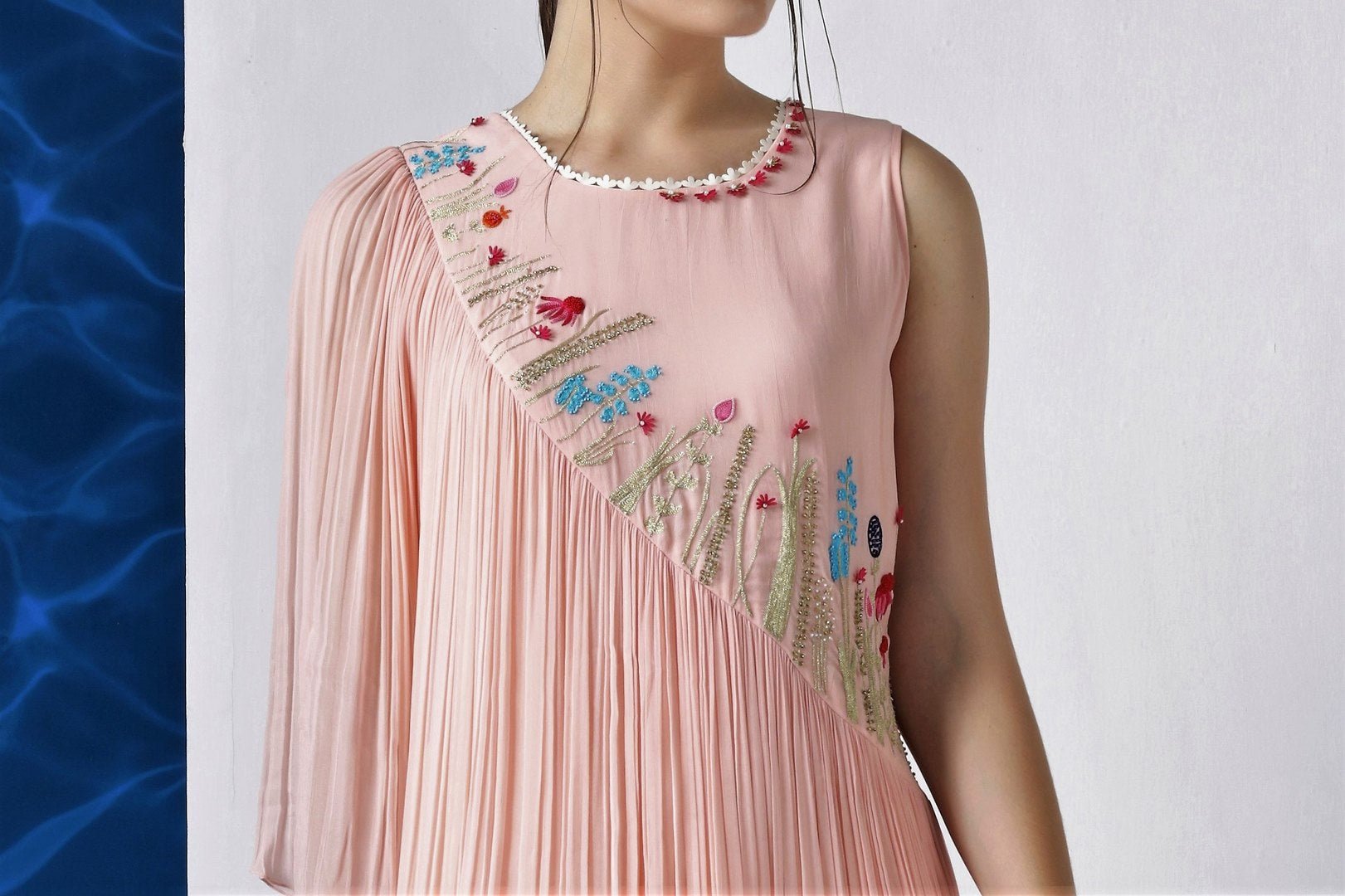 Shop peach color embroidered asymmetric dress with draped sleeve online in USA at Pure Elegance. Make your wardrobe an eclectic mix of alluring silhouettes and colors with a range of Indian designer clothes available at our clothing store in USA. -embroidery
