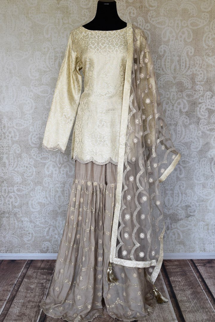 Shop cream embroidered Banarasi silk suit online in USA with grey silk sharara. Keep your wardrobe update with latest Indian clothing from Pure Elegance Indian fashion store in USA. Shop beautiful Indian designer lehengas, Anarkali suits, gowns for Indian women in USA from our online store.-full view