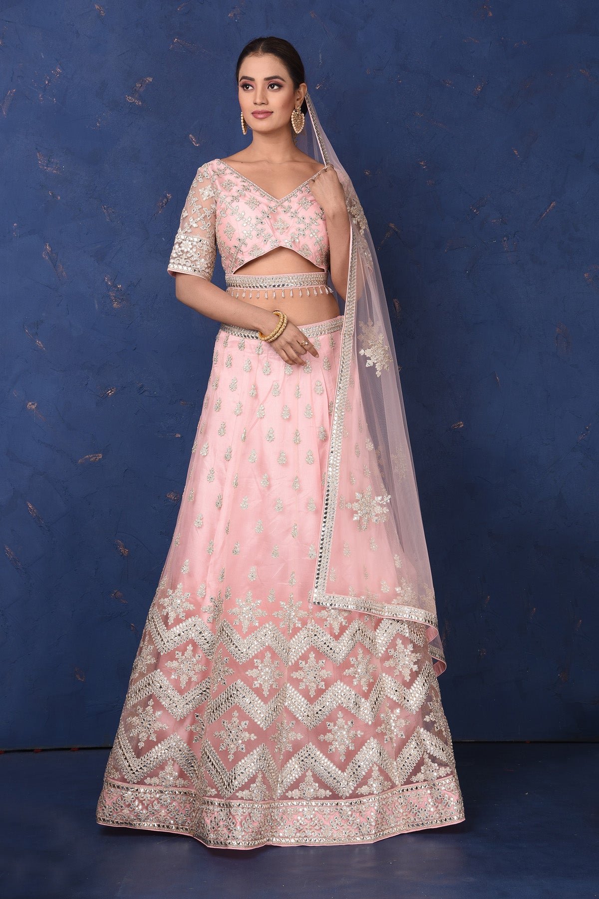 Shop powder pink embroidered net lehenga online in USA with dupatta, Be the center of attraction on festive occasions in beautiful designer suits, dresses, lehengas, designer gowns, from Pure Elegance Indian fashion store in USA.-front