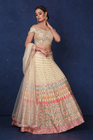 Buy stunning cream embroidered designer off-shoulder lehenga online in USA with dupatta. Set fashion goals on special occasions in exclusive designer lehengas, Indian suits, Anarkali dresses, designer gowns, bridal lehengas from Pure Elegance Indian fashion store in USA.-front