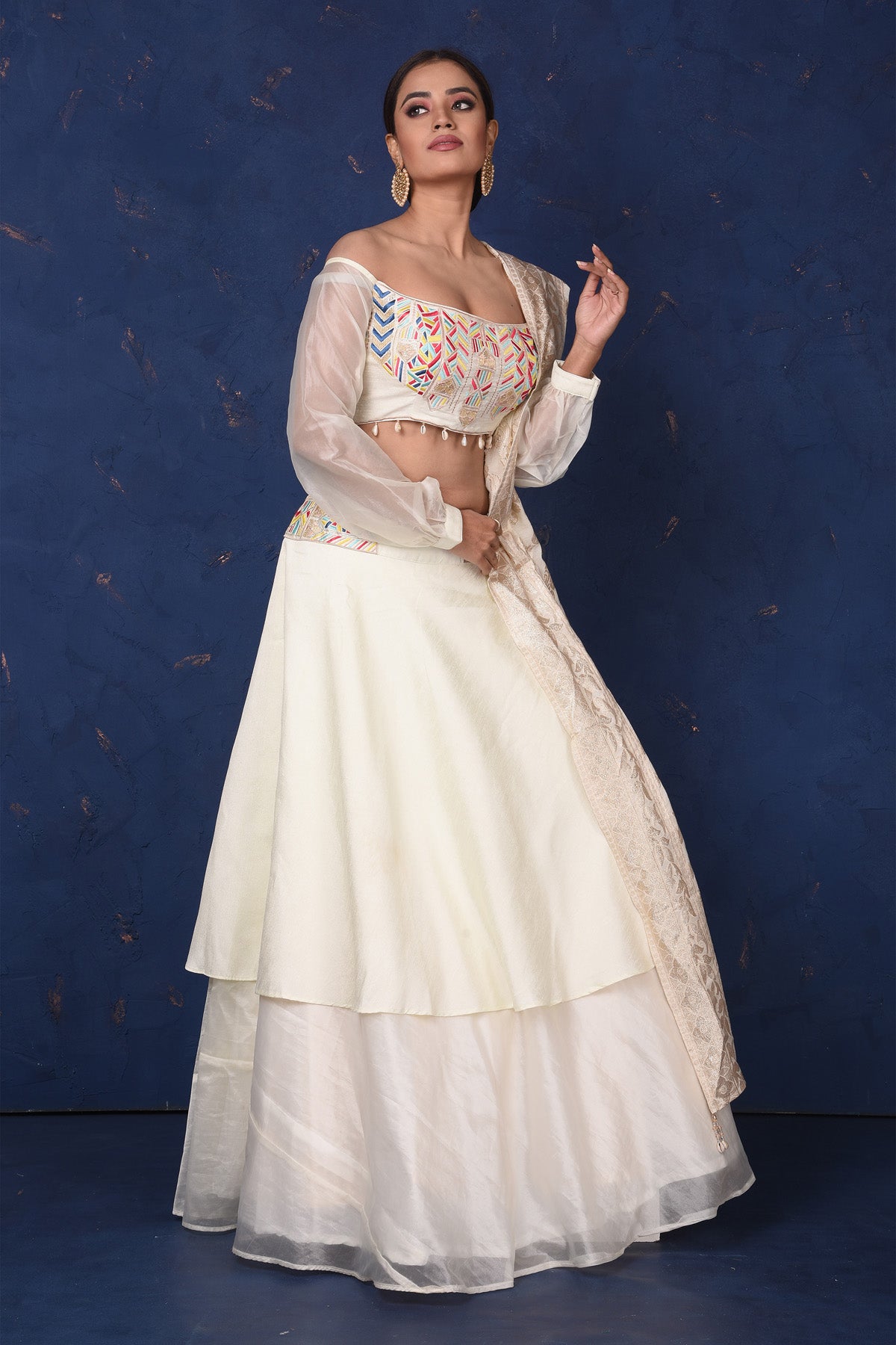 Shop elegant cream embroidered off-shoulder designer lehenga online in USA with dupatta. Set fashion goals on special occasions in exclusive designer lehengas, Indian suits, Anarkali dresses, designer gowns, bridal lehengas from Pure Elegance Indian fashion store in USA.-side