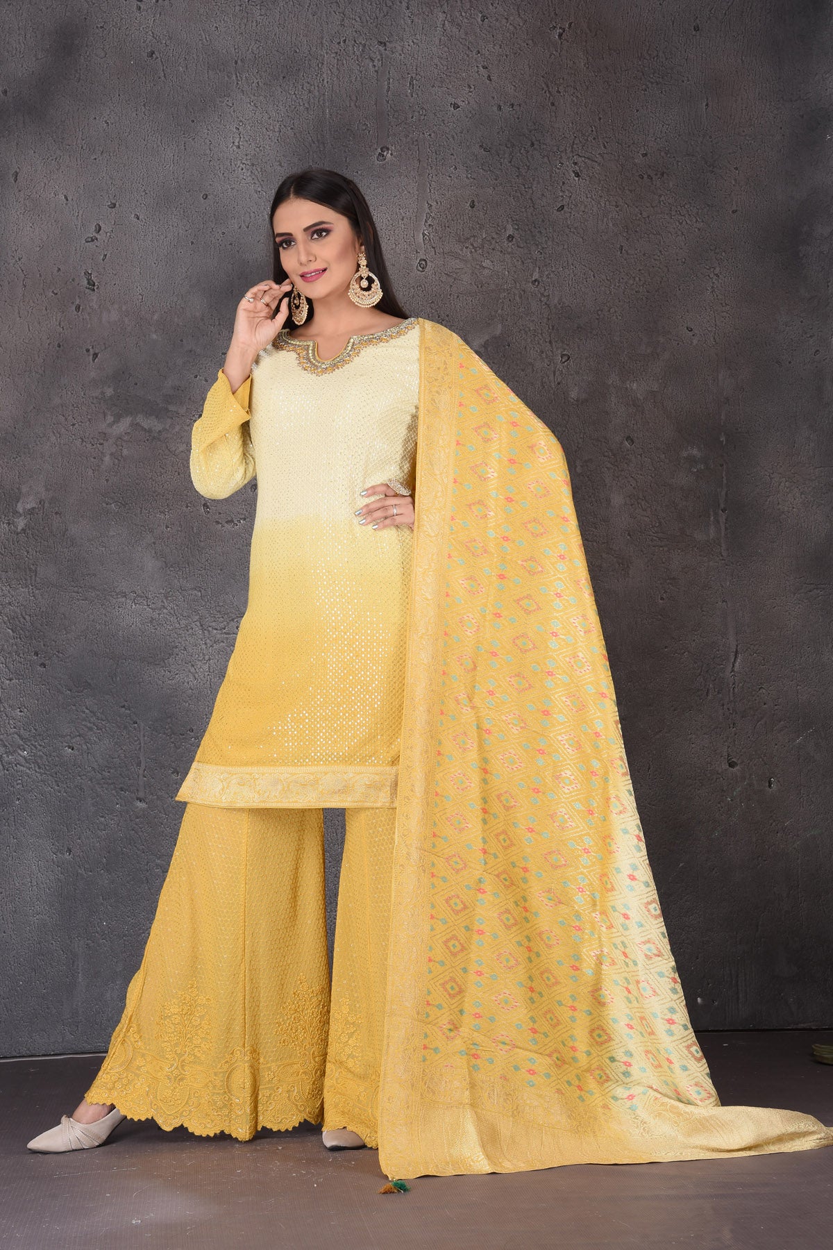 Buy stunning yellow embroidered sharara suit online in USA with dupatta. Look elegant at weddings and festive occasions in exclusive designer suits, designer gowns, Anarkali suits, sharara suits, bridal gowns, palazzo suits, designer lehenga from Pure Elegance Indian clothing store in USA.-front