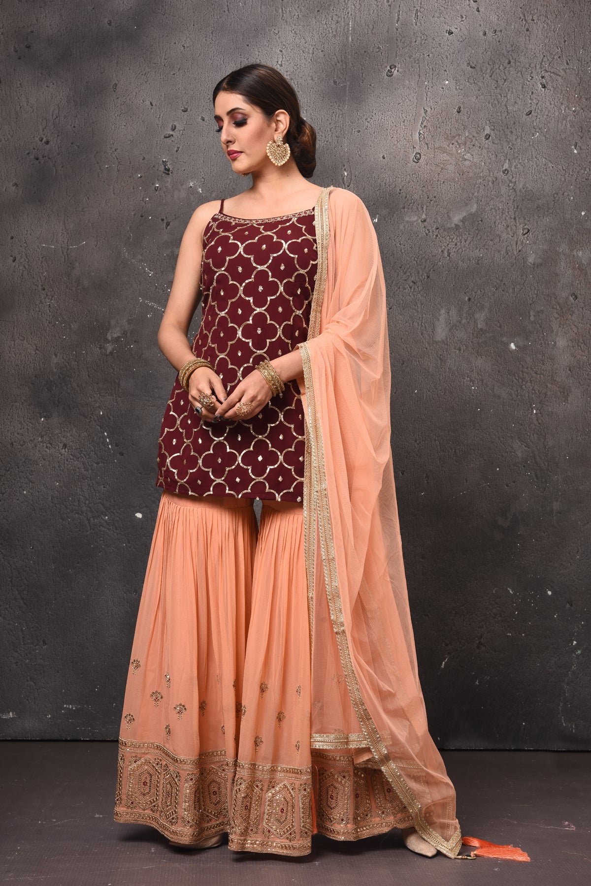 Buy stunning maroon and peach embroidered sharara suit online in USA. Get set for weddings and festive occasions in exclusive designer Anarkali suits, wedding gown, salwar suits, gharara suits, Indowestern dresses from Pure Elegance Indian fashion store in USA.-front