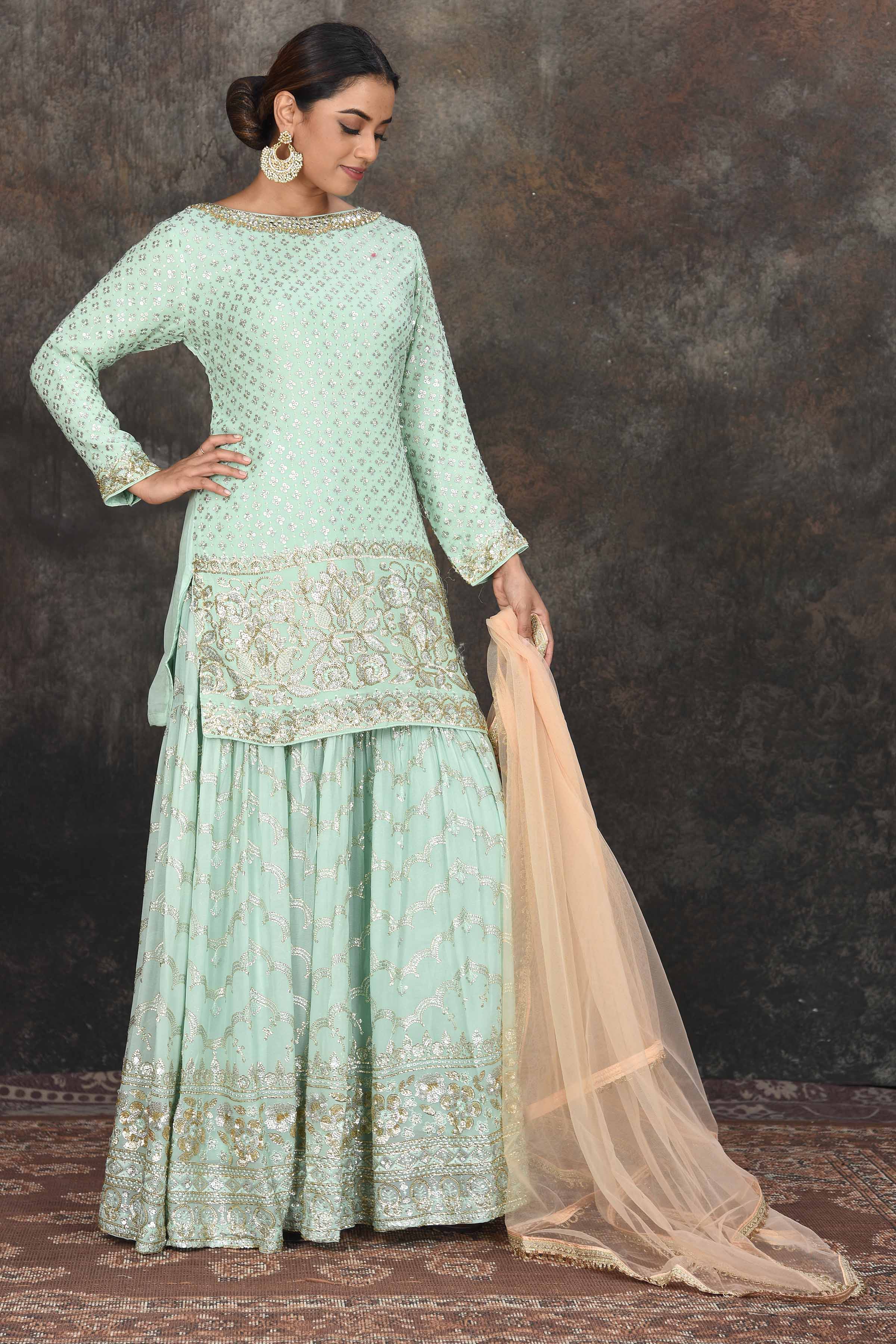 Shop beautiful mint green embroidered sharara suit online in USA with peach dupatta. Dazzle at sangeet and wedding occasions in this beautiful designer lehengas, Anarkali suits, sharara suit, bridal gowns, bridal lehengas from Pure Elegance Indian fashion store in USA.-front