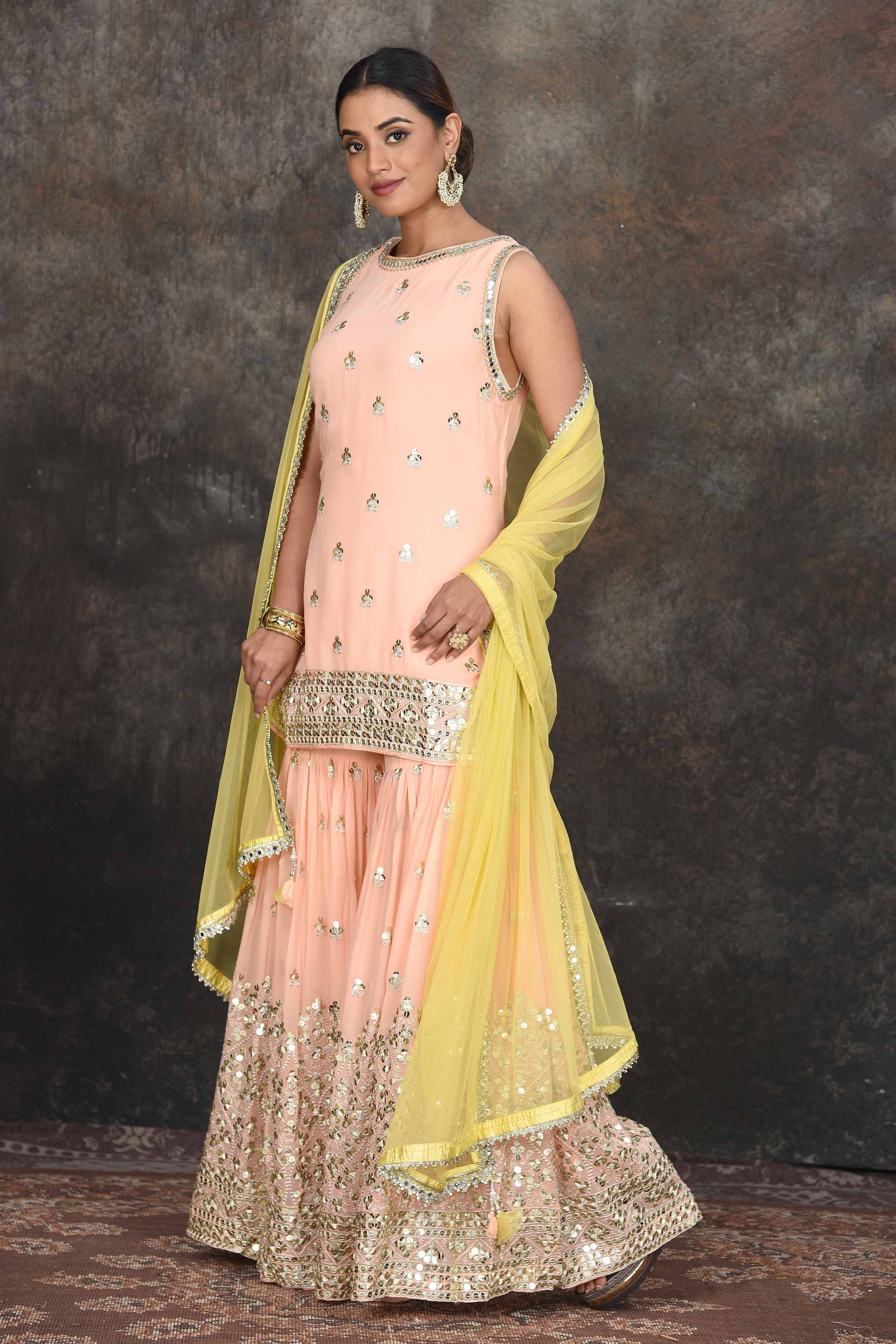 Shop beautiful peach embroidered sharara suit online in USA with yellow dupatta. Dazzle at sangeet and wedding occasions in this beautiful designer lehengas, Anarkali suits, sharara suit, bridal gowns, bridal lehengas from Pure Elegance Indian fashion store in USA.-side