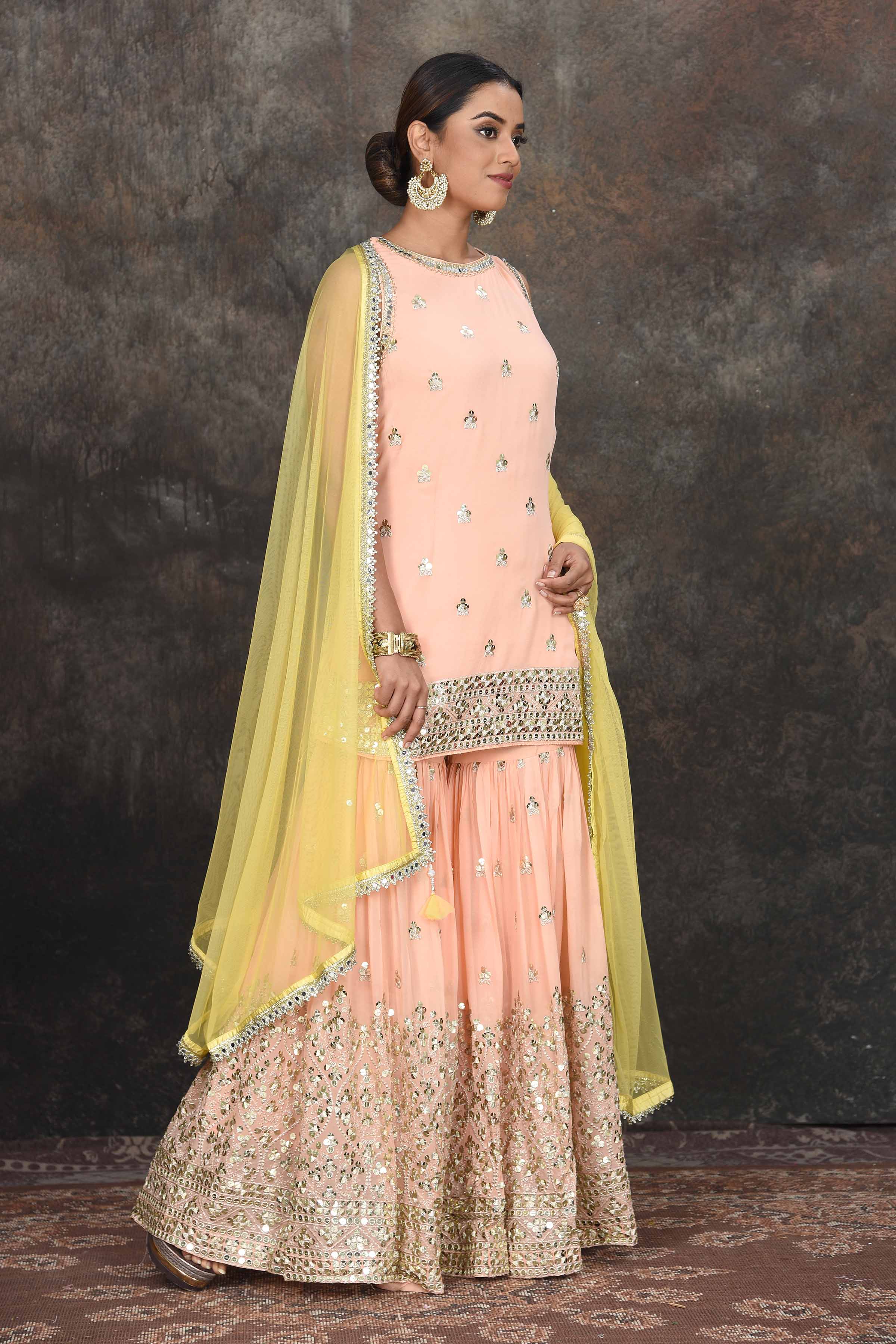 Shop beautiful peach embroidered sharara suit online in USA with yellow dupatta. Dazzle at sangeet and wedding occasions in this beautiful designer lehengas, Anarkali suits, sharara suit, bridal gowns, bridal lehengas from Pure Elegance Indian fashion store in USA.-right