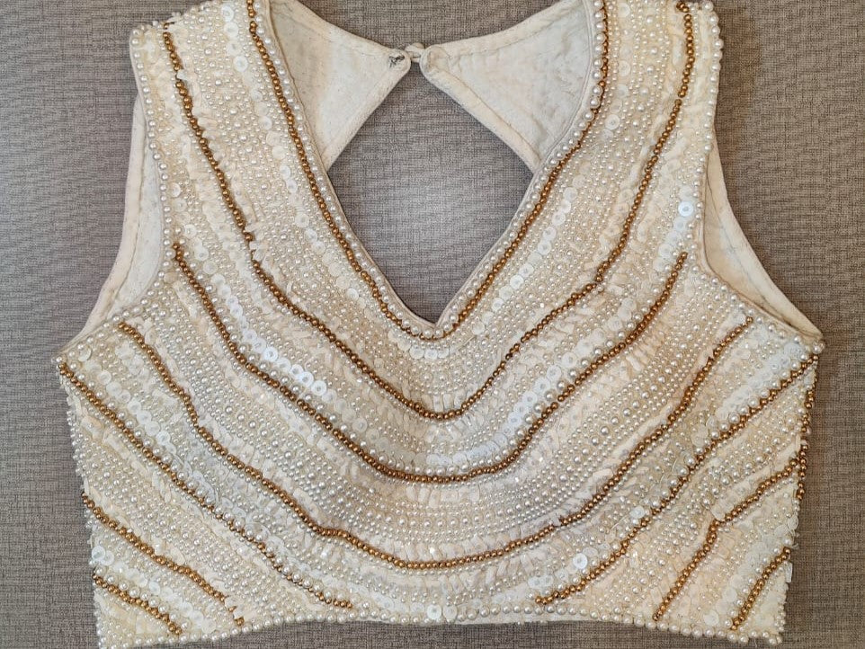 Buy beautiful off-white bead and shell work sleeveless saree blouse online in USA. Elevate your Indian saree style with exquisite readymade sari blouse, embroidered saree blouses, Banarasi saree blouse, designer sari blouse, choli-cut blouses from Pure Elegance Indian clothing store in USA.-full view