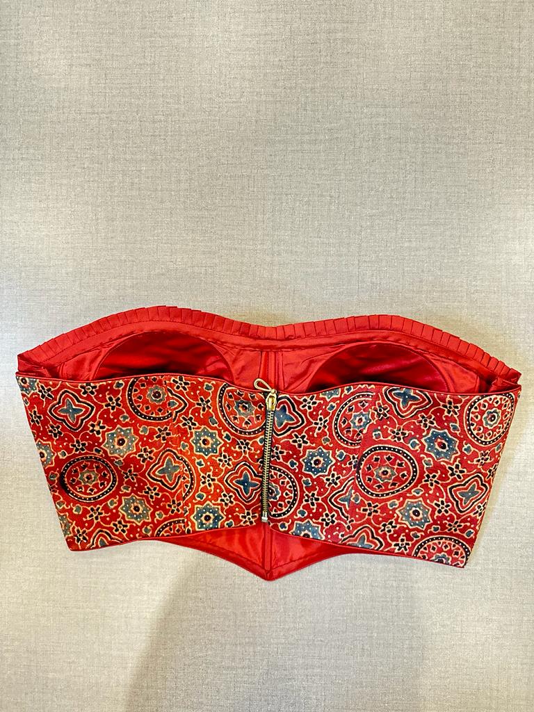 Shop stunning red Ajrak corset blouse online in USA. Elevate your saree style with exquisite readymade saree blouses, embroidered saree blouses, Banarasi saree blouse, designer saree blouse, choli-cut blouses, corset blouses from Pure Elegance Indian clothing store in USA.-back