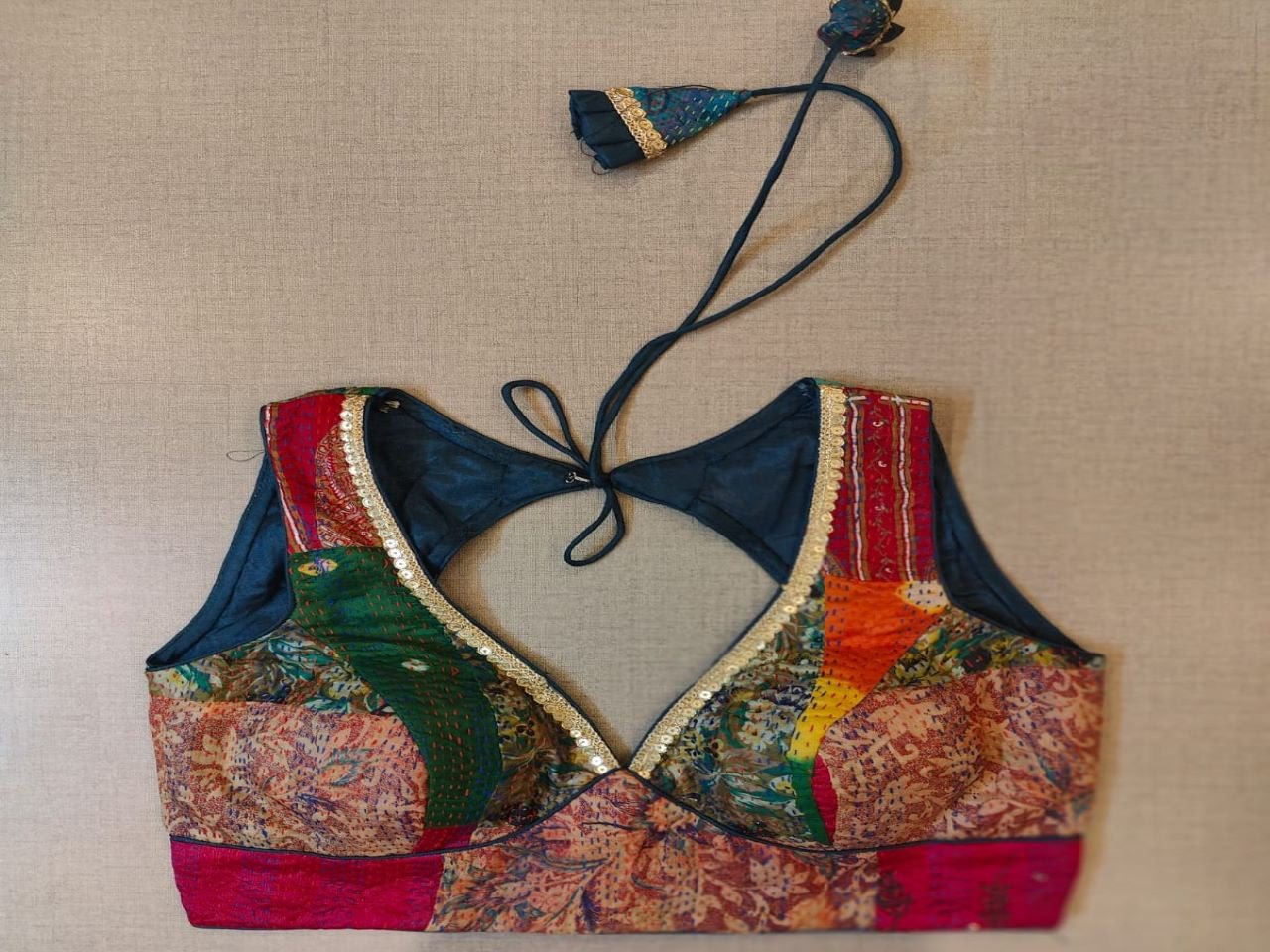 Buy a navy multicolor printed padded saree blouse, that has a V-neck, short sleeves, tie-up detail at the back, hook, and eye closure. Let your aura shine throughout by wearing this designer saree blouse. Pair this fashionable blouse with a beautiful printed sari and statement neck piece and you are good to go. - Front View