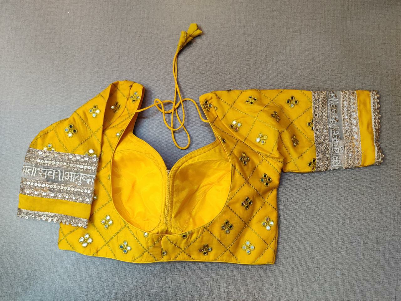 Buy this exquisite yellow designer saree blouse online with mirror work in USA. Add yellow embroidered designer saree blouse with mirror work and mantra lace border with sweetheart neckline, long sleeve, banarasi sari blouse, sari blouses online, sari blouse from Pure Elegance Indian fashion store in USA.- Back.
