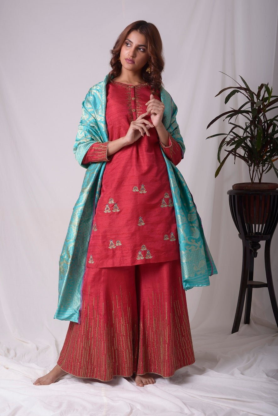 PBuy elegant red silk suit online in USA. Suit has gold sequence design work. Kurta has 3/4 length sleeves, high neck, red palazzo and blue dupatta. Simple look makes it elegant.Be the talk of parties and weddings with exquisite designer gowns from Pure Elegance Indian clothing store in USA. Shop online now.-full view